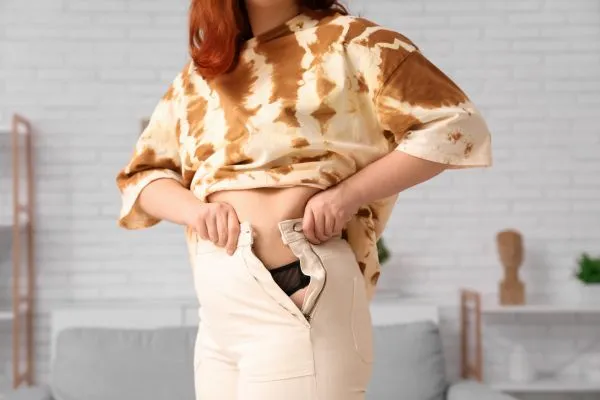 Image of woman trying to do her trousers up after pregnancy weight gain Market Drayton